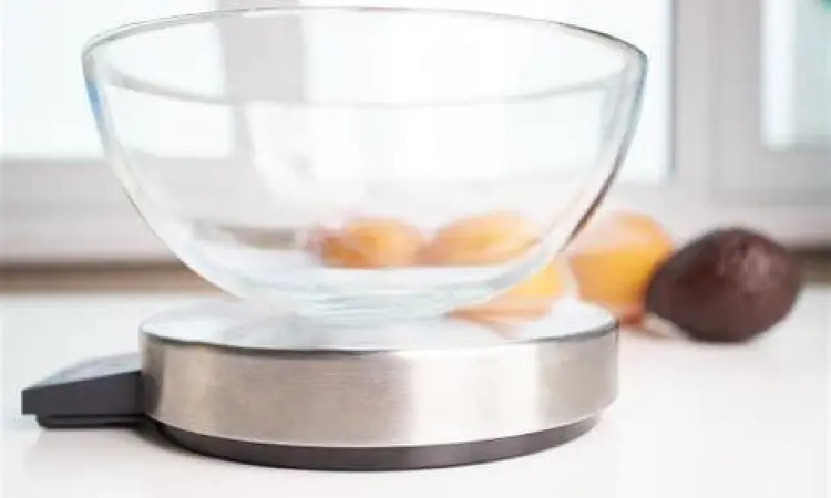 Menimbang Bahan Makanan Seseorang menimbang tepung menggunakan timbangan gram