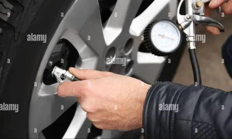 Mekanik mengecek tekanan ban mobil dengan alat ukur