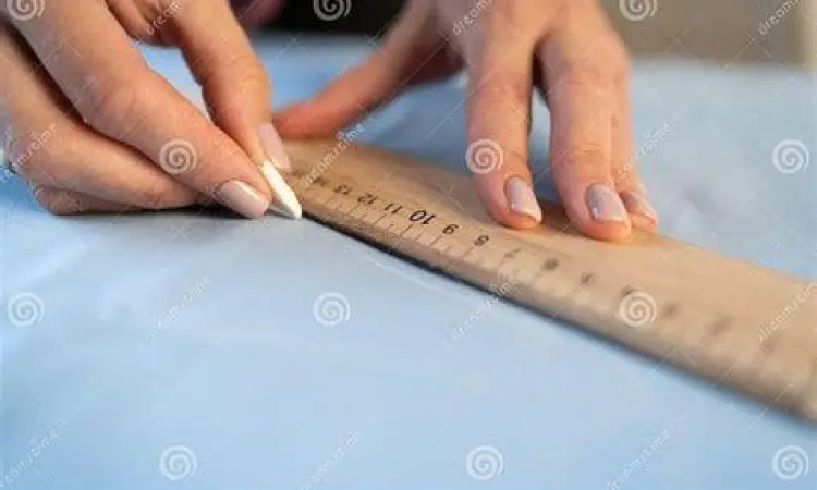 Penjahit mengukur kain dengan penggaris panjang
